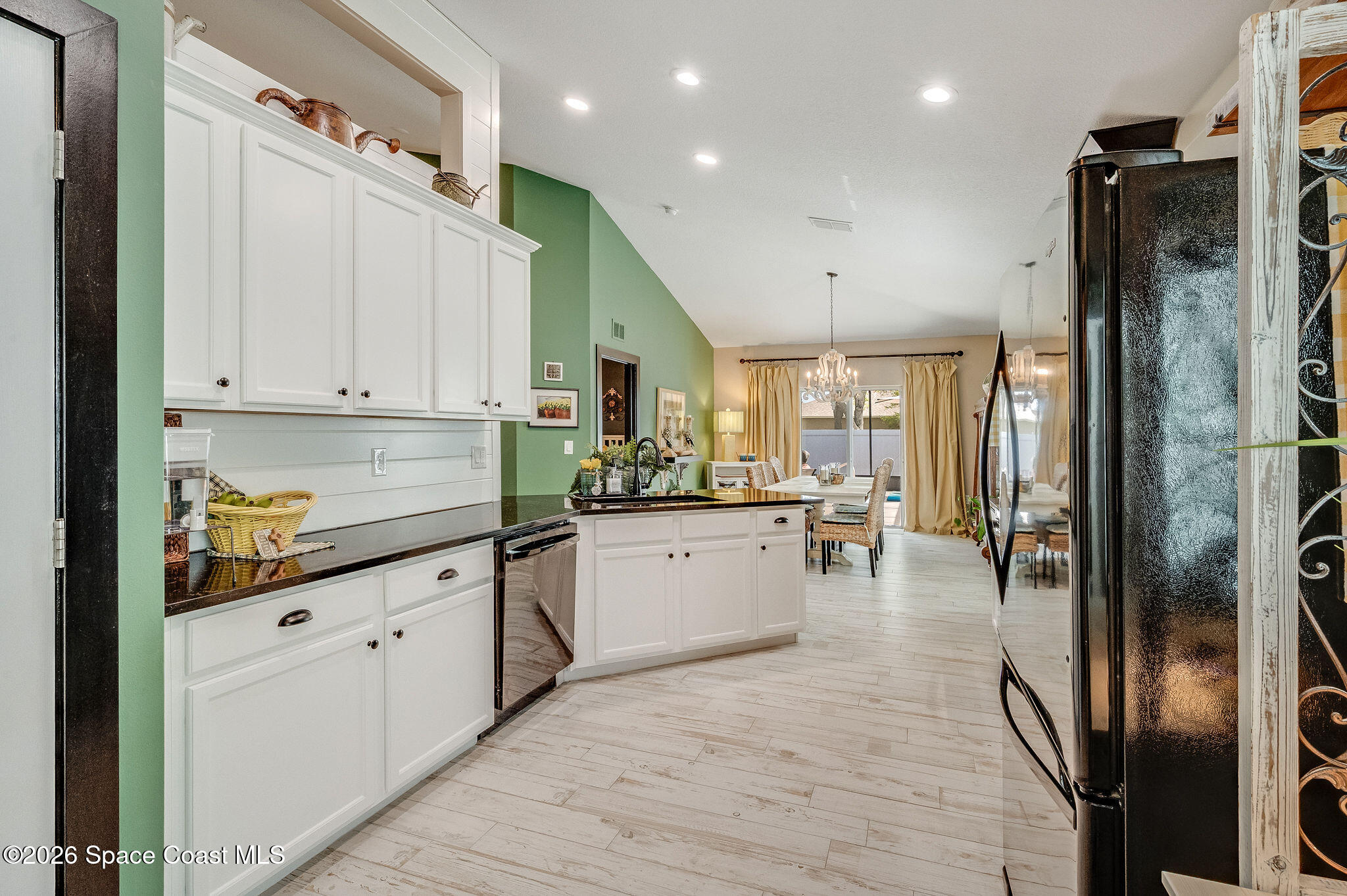 3911 Joslin Way Melbourne, FL 32904 - Photo 23 of 63 a kitchen with stainless steel appliances granite countertop a refrigerator a sink dishwasher and white cabinets with wooden floor