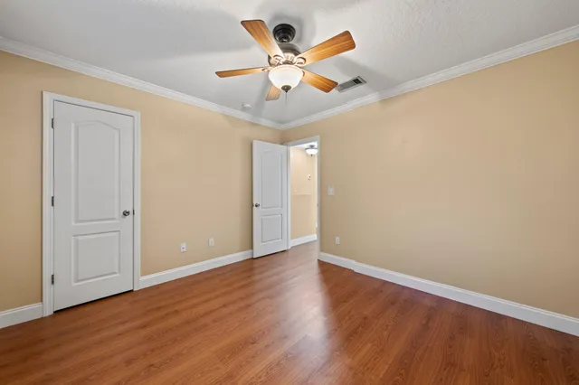 an empty room with wooden floor and ceiling fan