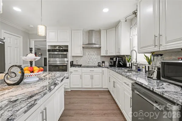 a kitchen with granite countertop a stove a sink and a refrigerator