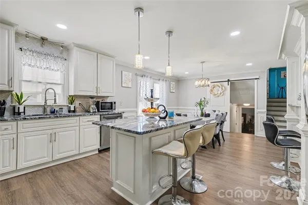 a kitchen with stainless steel appliances kitchen island granite countertop a sink cabinets and wooden floor