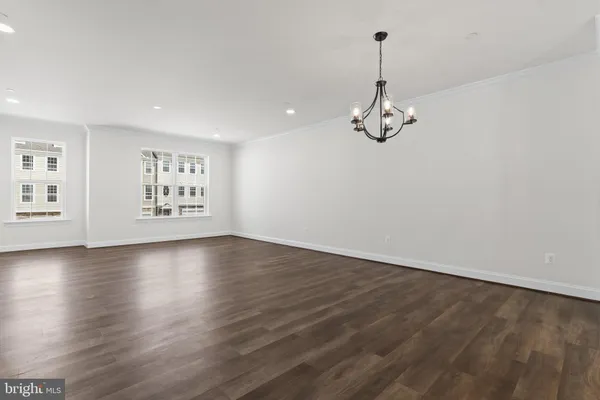 an empty room with wooden floor ceiling fan and windows