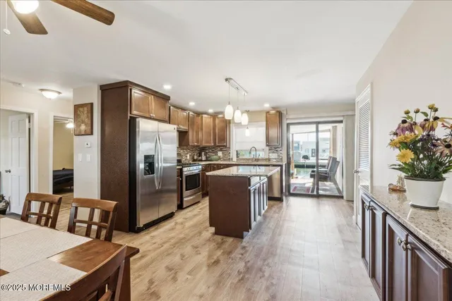 a kitchen with stainless steel appliances kitchen island granite countertop a refrigerator a sink a stove and white cabinets