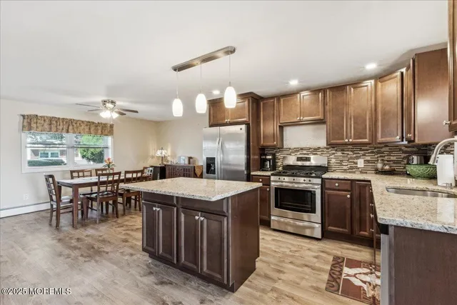 a kitchen with stainless steel appliances granite countertop a stove top oven a sink dishwasher a dining table and chairs with wooden floor