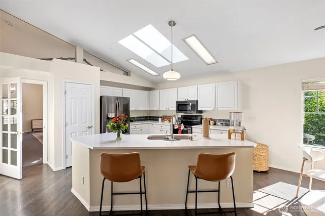 a kitchen with stainless steel appliances kitchen island granite countertop a sink a stove a dining table and chairs