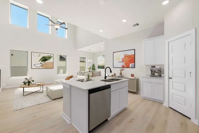 a view of a living room kitchen with a sink dishwasher stove and white cabinets with wooden floor