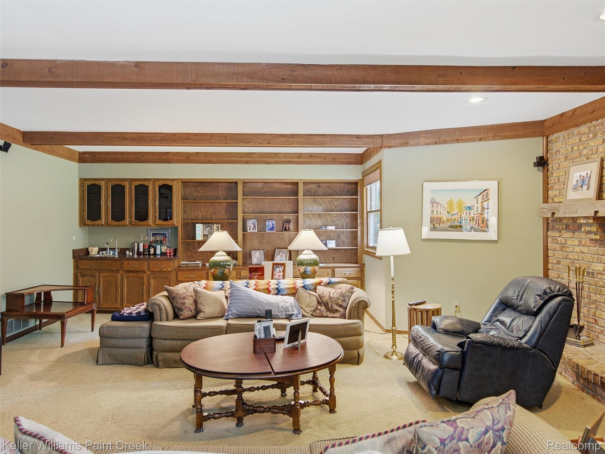 2950 Leyton Court Rochester, MI 48306 - Photo 16 of 46 Exposed wood beams, built-in shelving, integrated wet bar with cabinetry, recessed lighting, and a brick fireplace