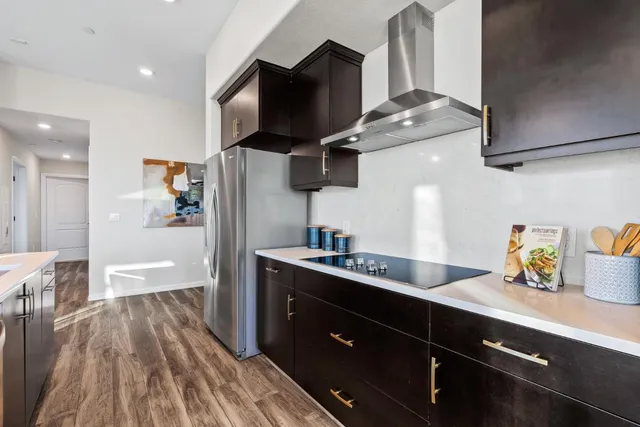 a large kitchen with stainless steel appliances a large counter top a stove a chimney a sink and a refrigerator