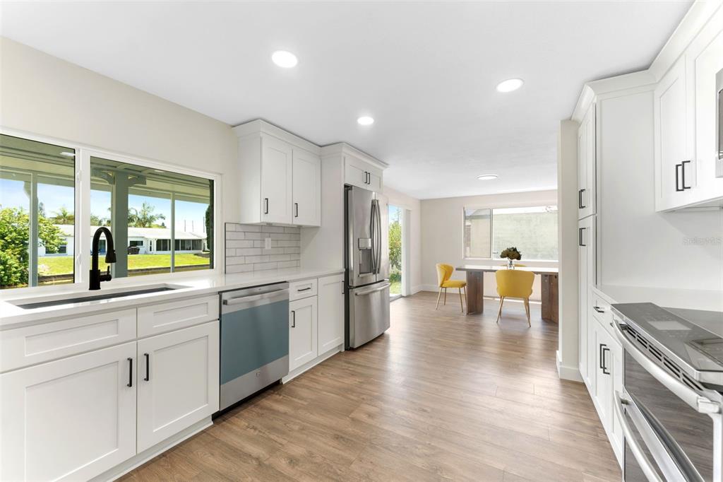 4016 Grayton Drive New Port Richey, FL 34652 - Photo 12 of 40 a large kitchen with kitchen island granite countertop a stove a sink a refrigerator and white cabinets with wooden floor
