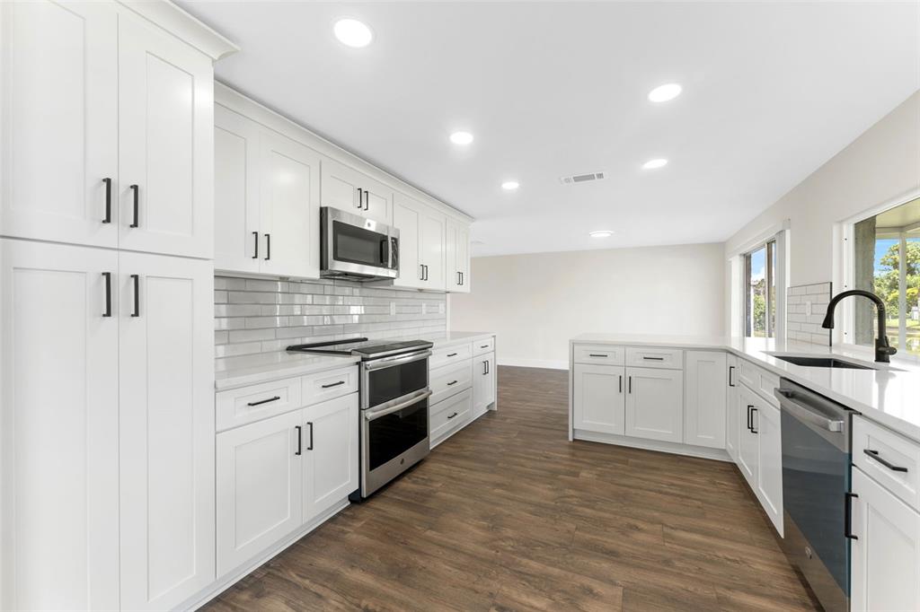 4016 Grayton Drive New Port Richey, FL 34652 - Photo 13 of 40 a large white kitchen with stainless steel appliances granite countertop a stove and a sink
