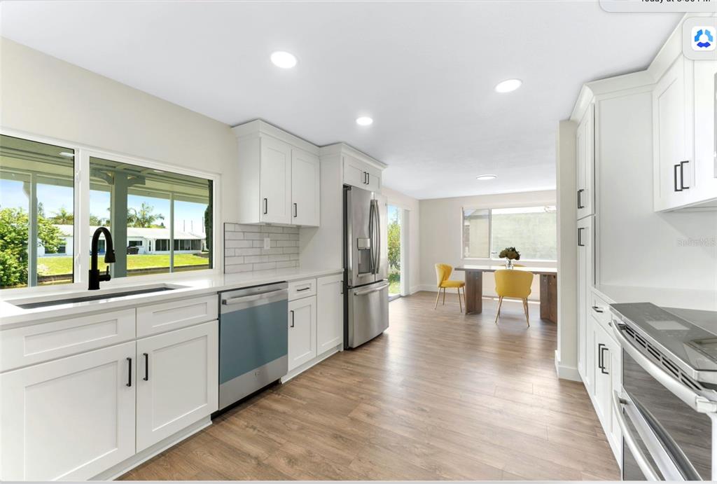 4016 Grayton Drive New Port Richey, FL 34652 - Photo 26 of 40 a kitchen with stainless steel appliances granite countertop a stove a sink a refrigerator and white cabinets with wooden floor