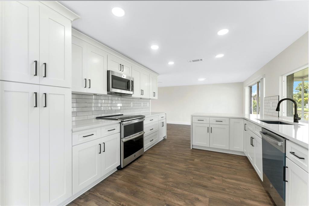 4016 Grayton Drive New Port Richey, FL 34652 - Photo 32 of 40 a large white kitchen with stainless steel appliances granite countertop a stove and a sink