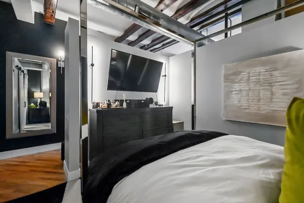 a bedroom with a bed and a flat tv screen on dresser