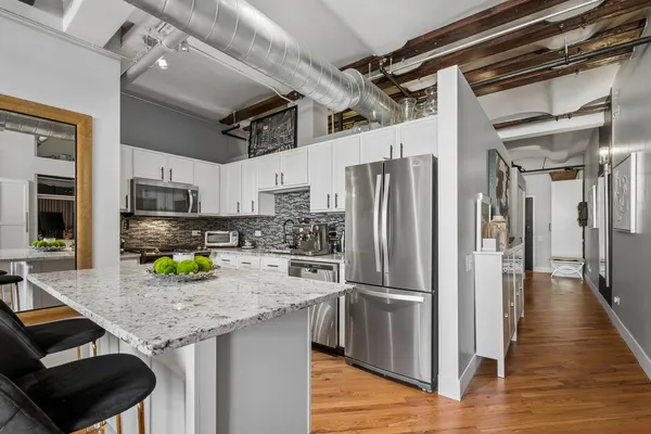 a kitchen with stainless steel appliances granite countertop a refrigerator a stove and a sink with wooden floor