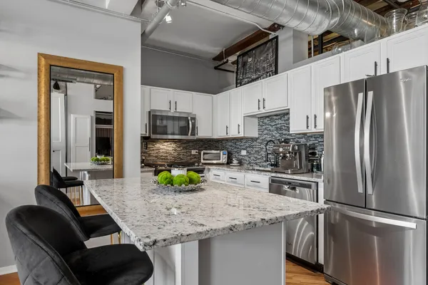 a kitchen with stainless steel appliances granite countertop a sink refrigerator and microwave