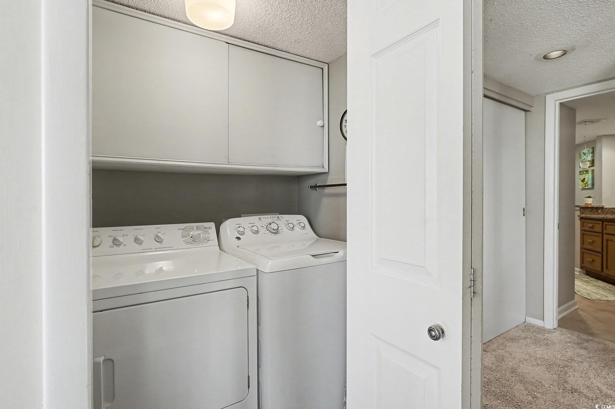 9650 Shore Drive, Unit 1507 Myrtle Beach, SC 29572 - Photo 13 of 39 Laundry room featuring cabinet space, a textured ceiling, light carpet, and separate washer and dryer