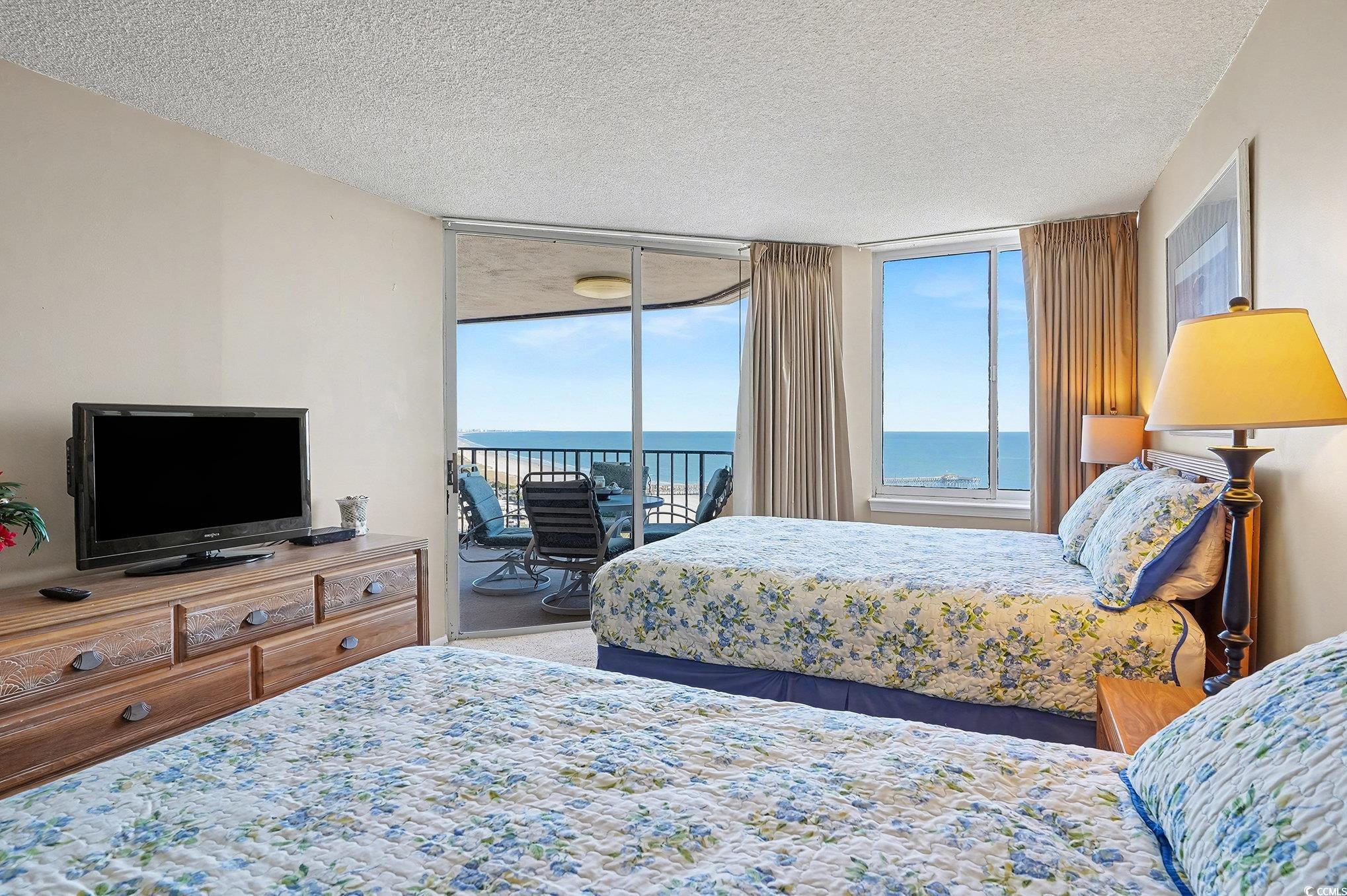 9650 Shore Drive, Unit 1507 Myrtle Beach, SC 29572 - Photo 17 of 39 Bedroom featuring a water view, a textured ceiling, access to outside, carpet, and floor to ceiling windows