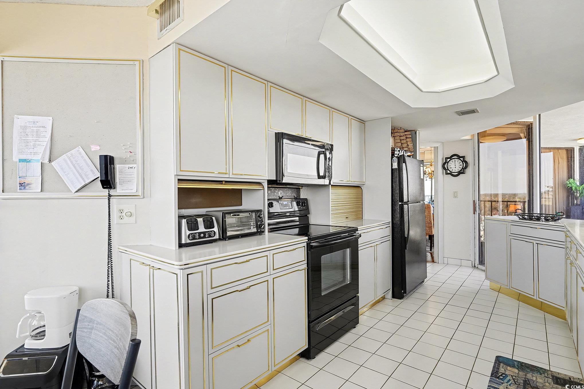 9650 Shore Drive, Unit 1507 Myrtle Beach, SC 29572 - Photo 9 of 39 Kitchen with black appliances, light countertops, white cabinetry, and light tile patterned flooring