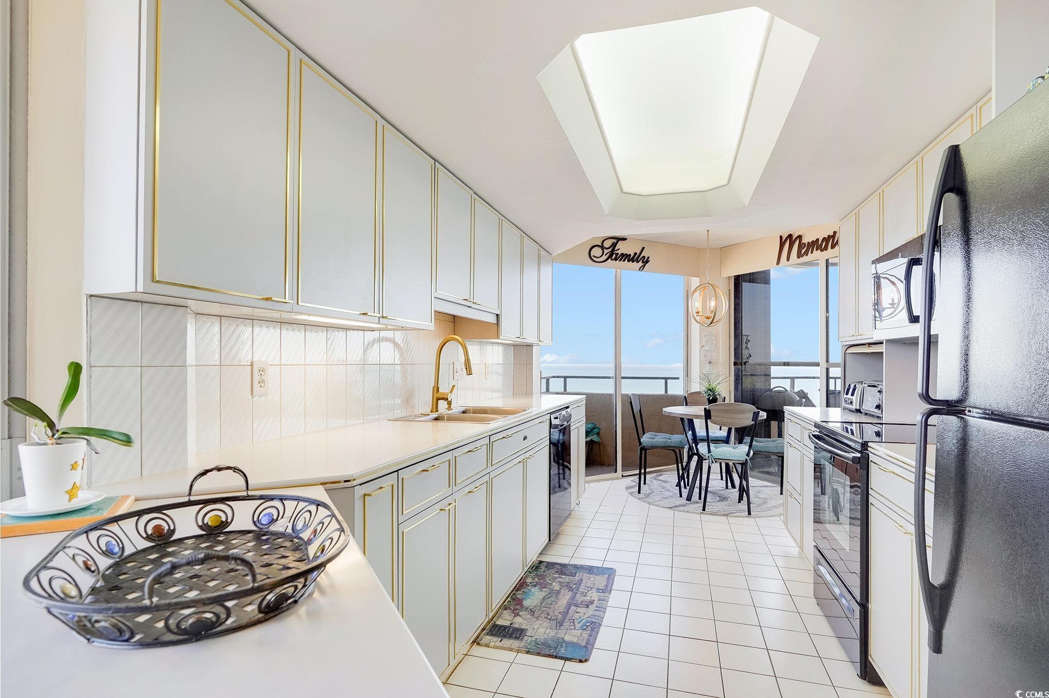 9650 Shore Drive, Unit 1507 Myrtle Beach, SC 29572 - Photo 10 of 39 Kitchen with black appliances, light countertops, white cabinets, backsplash, and light tile patterned floors