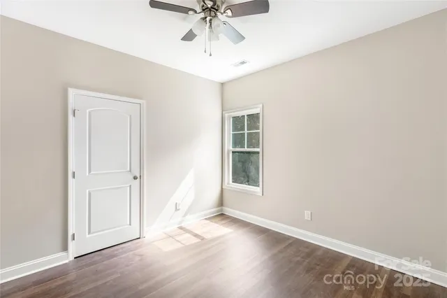 an empty room with wooden floor fan and windows