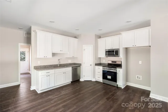 a kitchen with granite countertop a stove top oven and cabinets
