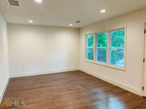 an empty room with wooden floor and windows