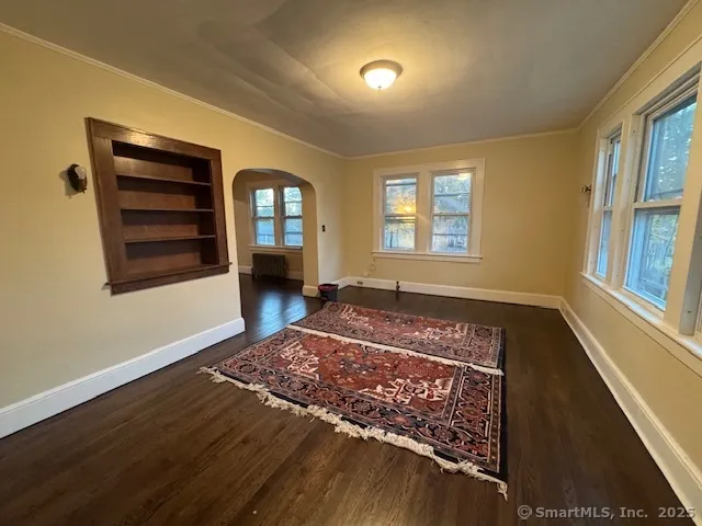 a view of an empty room with a window and wooden floor