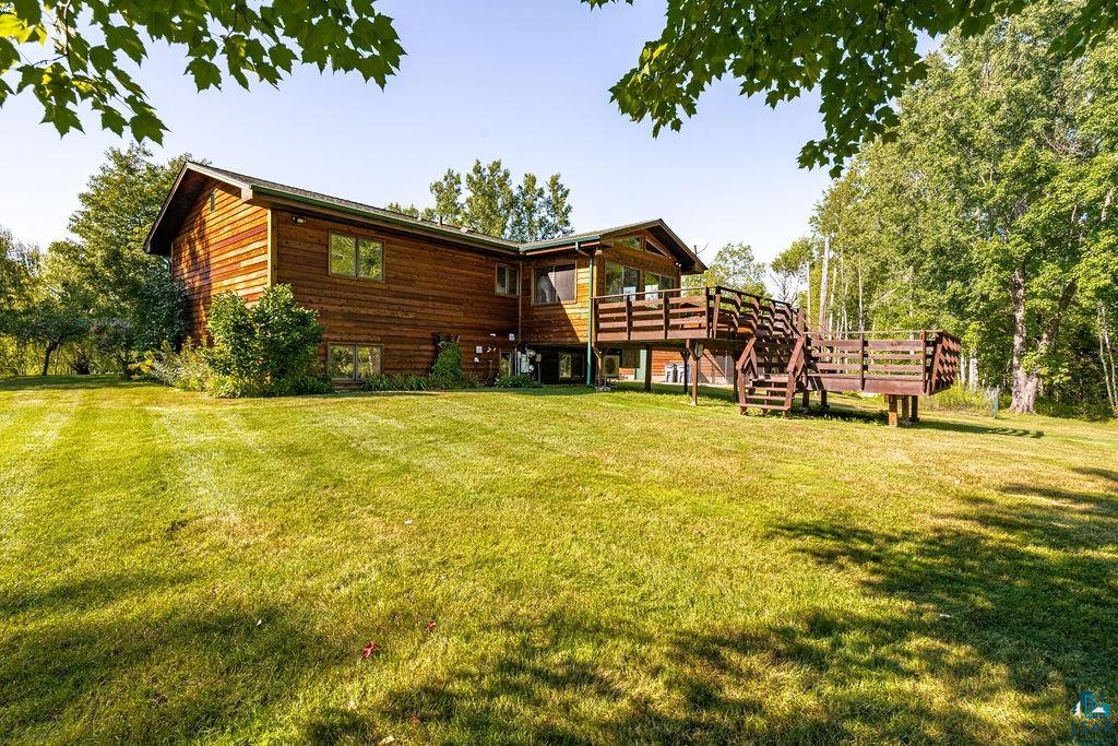 5370 Ugstad Road Hermantown, MN 55811 - Photo 59 of 68 Wood-sided exterior with multiple windows, an elevated wood deck, and a spacious grassy yard