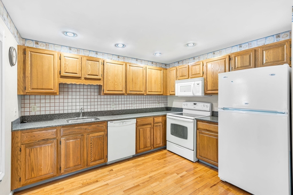 4 Country Meadow Road, Unit 4 Haverhill, MA 01832 - Photo 6 of 29 a kitchen with stainless steel appliances granite countertop a refrigerator a sink dishwasher a stove and white countertops with wooden floor