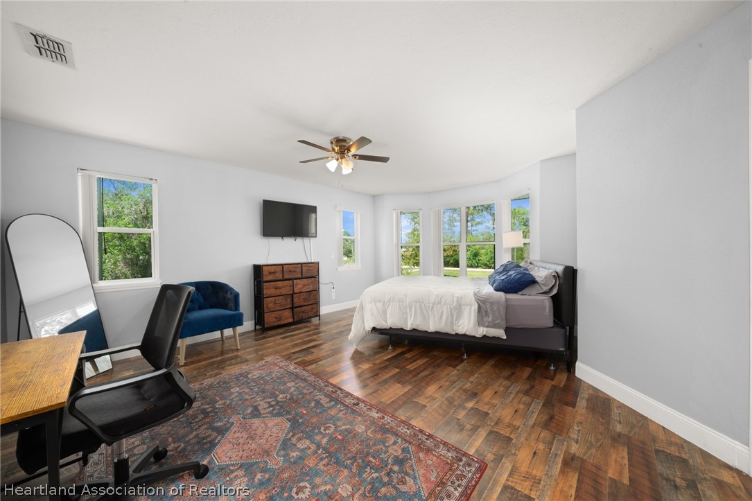 5731 Wolf Lake Road Sebring, FL 33875 - Photo 24 of 45 a bedroom with a bed a chair and a chandelier