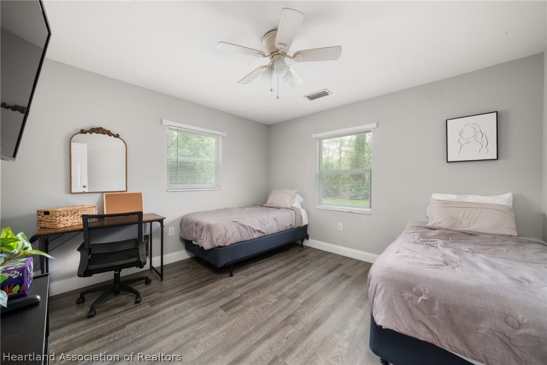 5731 Wolf Lake Road Sebring, FL 33875 - Photo 37 of 45 a bedroom with a bed a desk and chair with wooden floor
