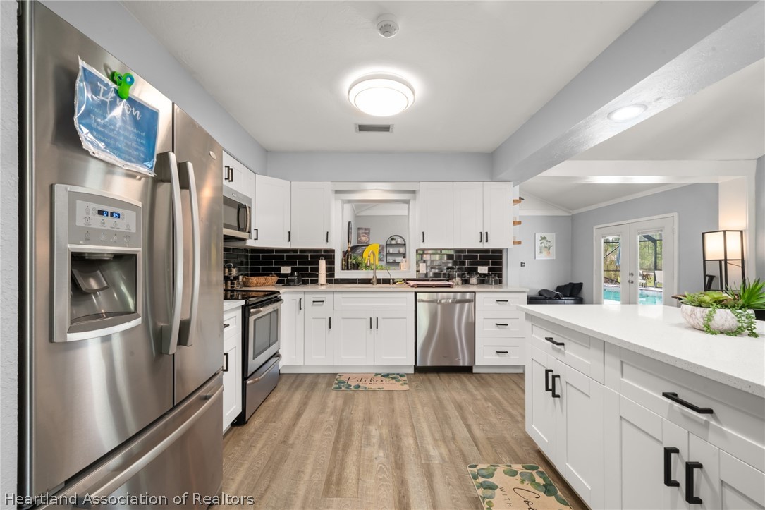 5731 Wolf Lake Road Sebring, FL 33875 - Photo 9 of 45 a kitchen with stainless steel appliances granite countertop a refrigerator sink and white cabinets