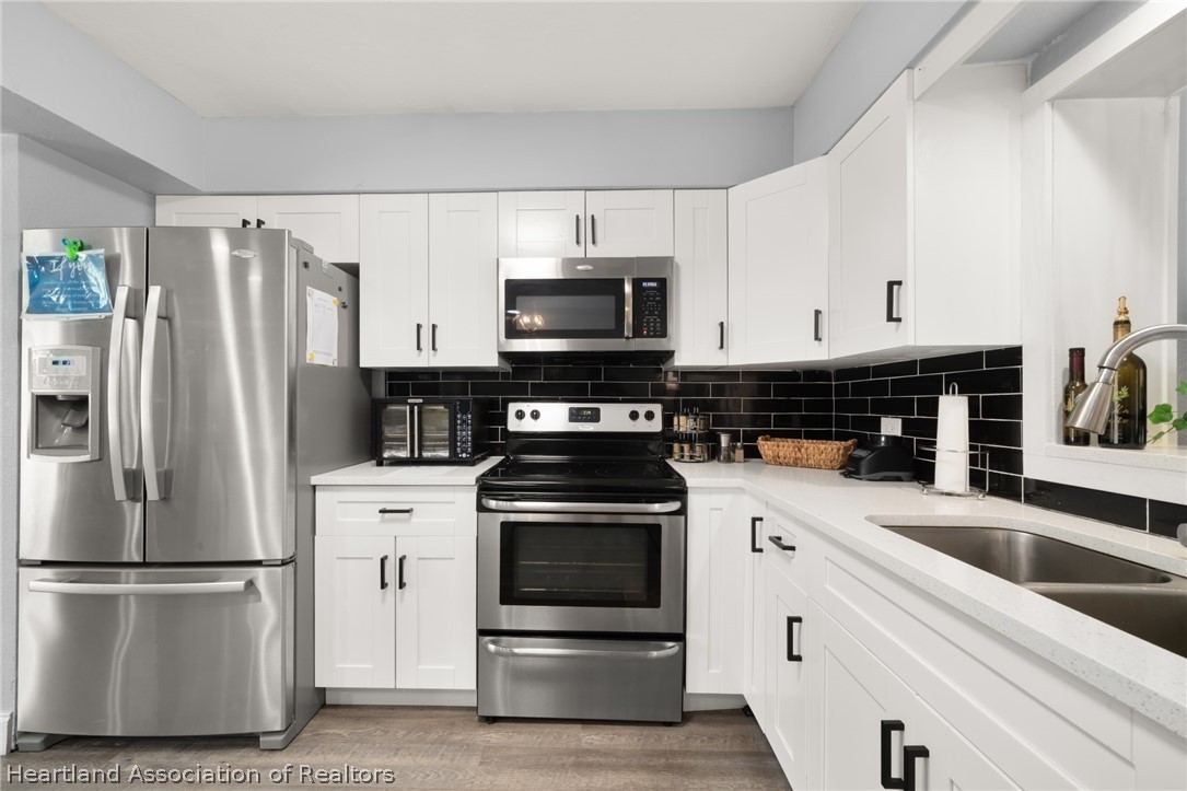 5731 Wolf Lake Road Sebring, FL 33875 - Photo 10 of 45 a kitchen with a refrigerator stove and white cabinets