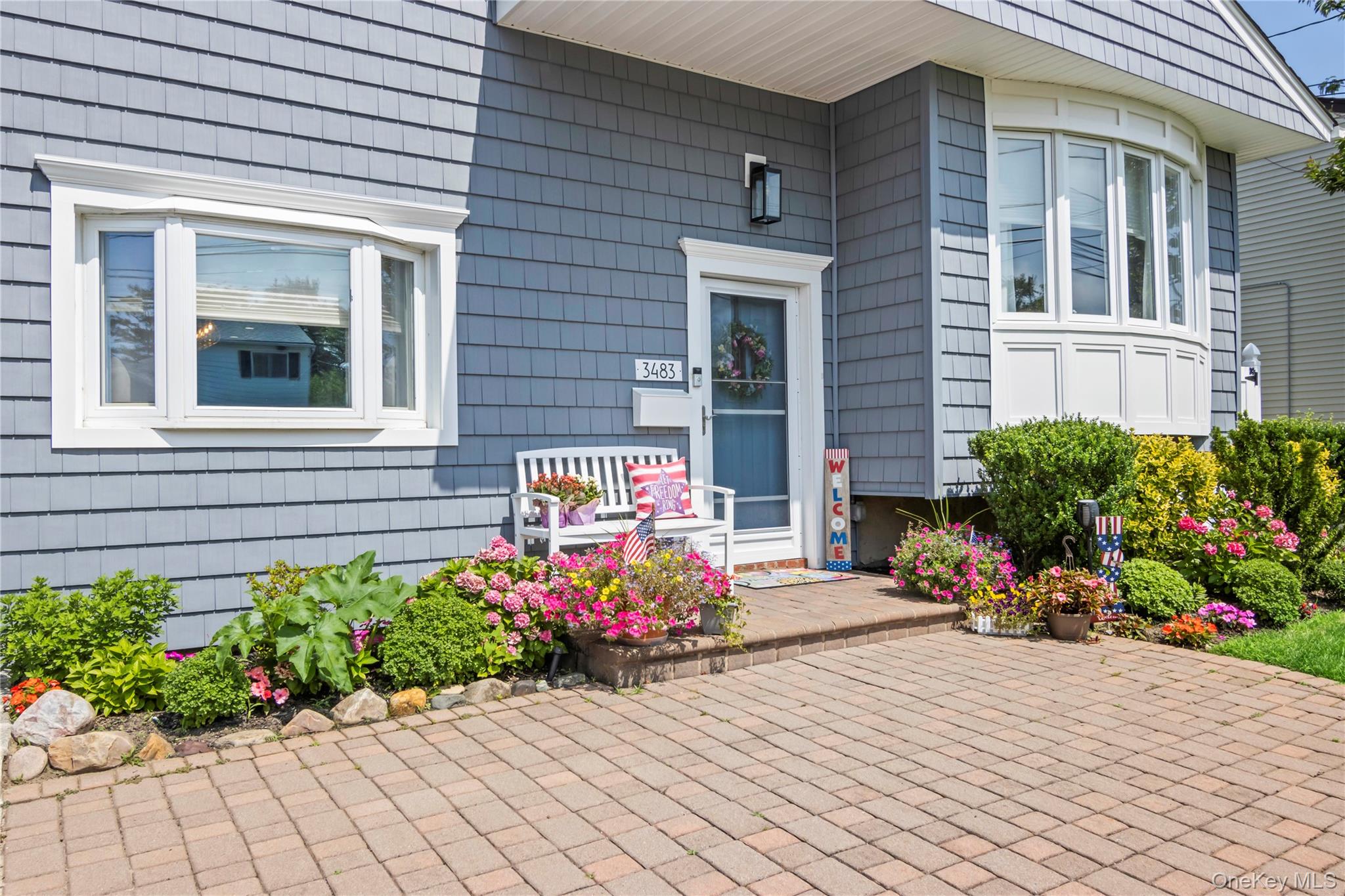 3483 Steven Road Baldwin, NY 11510 - Photo 30 of 30 a front view of a house with a yard and a bench