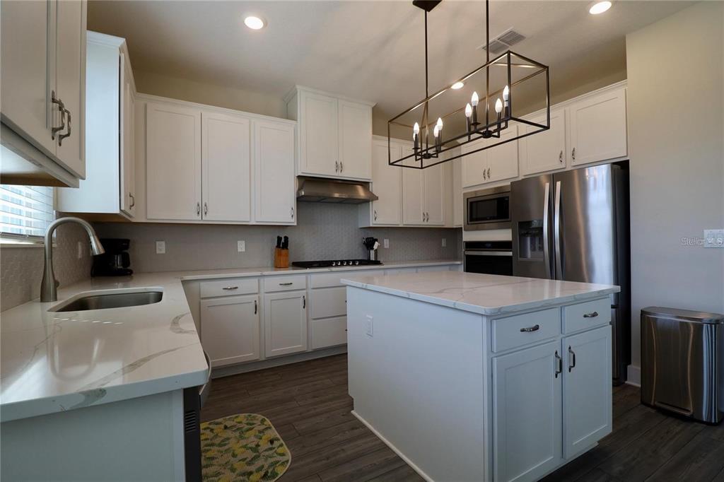 7955 Delwin Lane Reunion, FL 34747 - Photo 11 of 25 a kitchen with kitchen island granite countertop stainless steel appliances a sink a stove a refrigerator a center island and cabinets