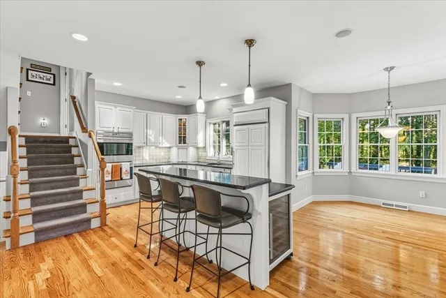 a kitchen with stainless steel appliances kitchen island granite countertop a table chairs in it and wooden floors