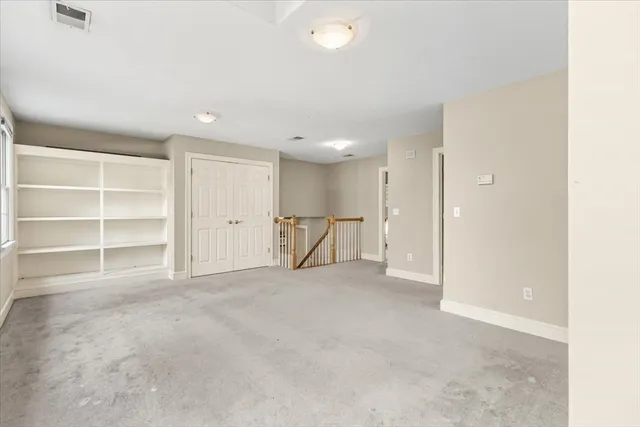 a view of an empty room with a cabinet and mirrors