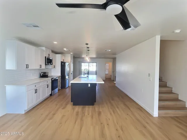 a large kitchen with cabinets wooden floor and stainless steel appliances