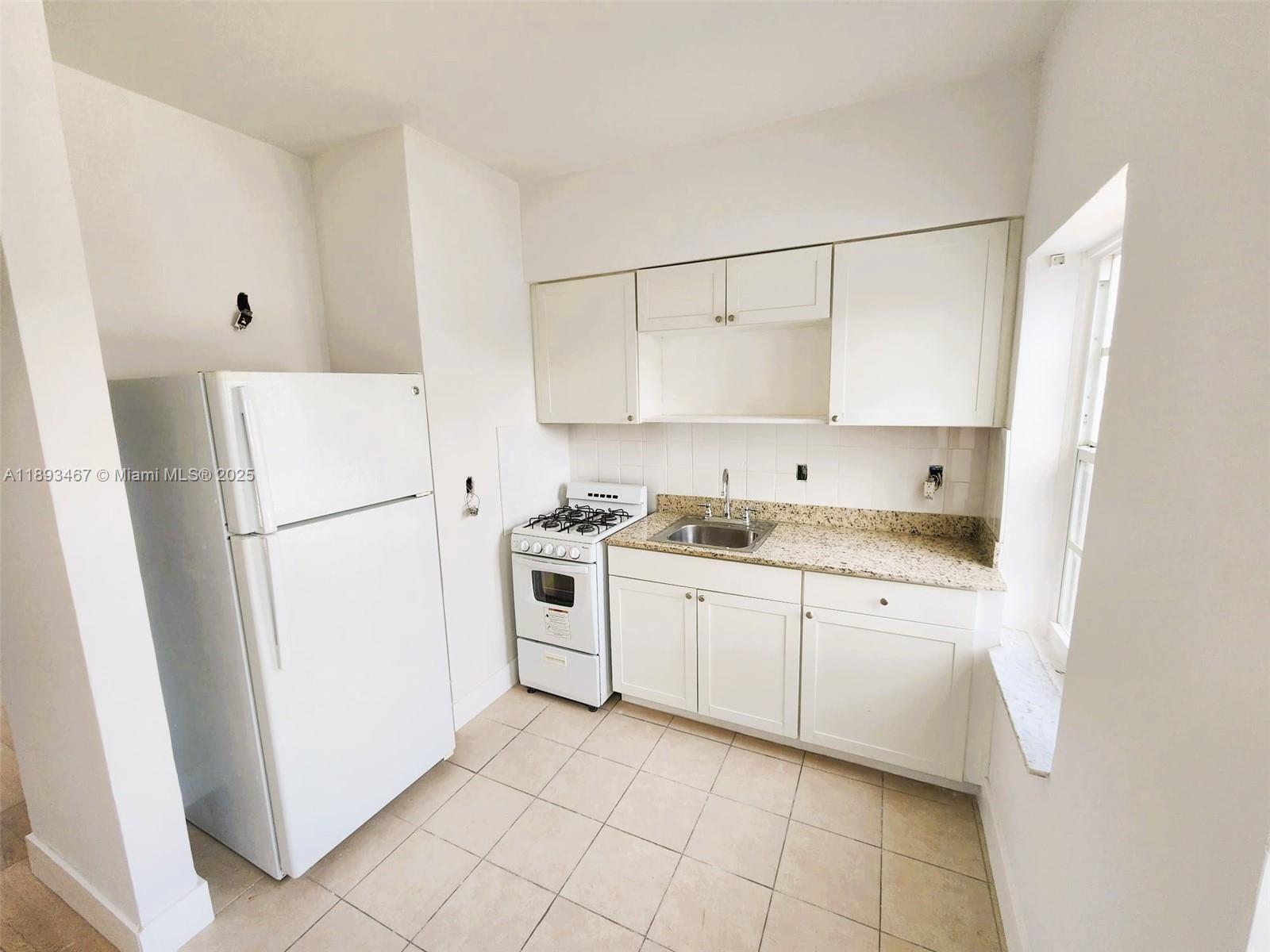 7611 Harding Avenue, Unit 8 Miami Beach, FL 33141 - Photo 4 of 19 a kitchen with cabinets a refrigerator and a stove