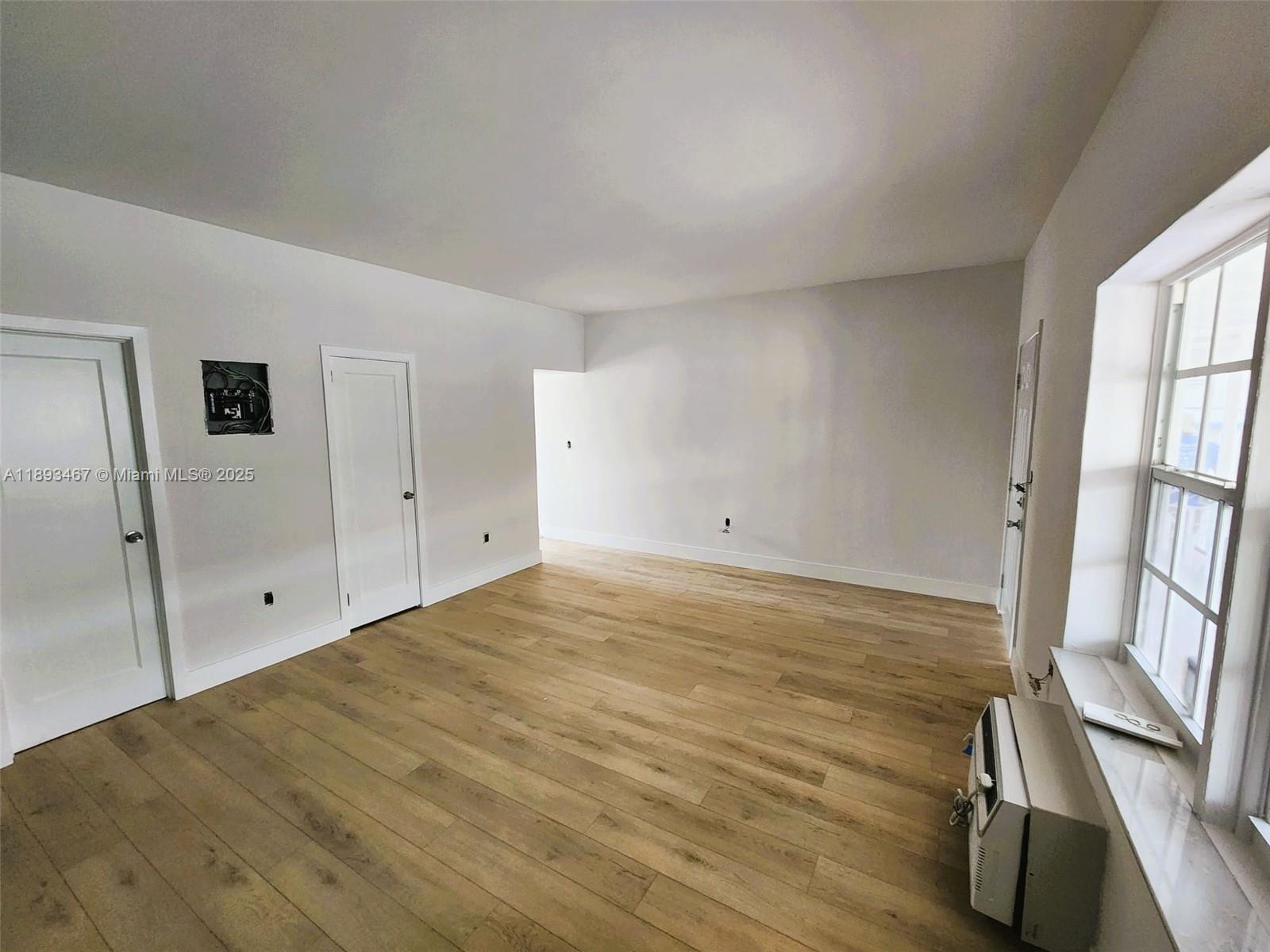 7611 Harding Avenue, Unit 8 Miami Beach, FL 33141 - Photo 7 of 19 a view of empty room with window and wooden floor