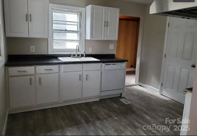 a kitchen with granite countertop white cabinets sink and window