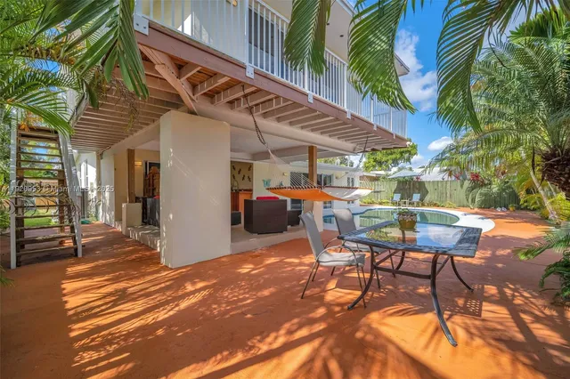 a view of a white house with a swimming pool and a lawn chairs under an umbrella