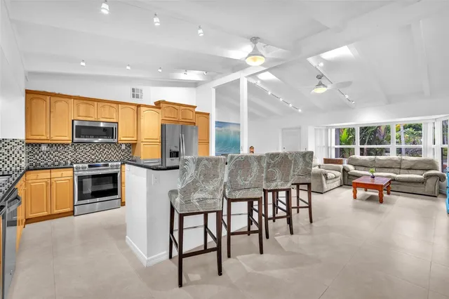 a kitchen with stainless steel appliances granite countertop a stove top oven a sink a dining table and chairs