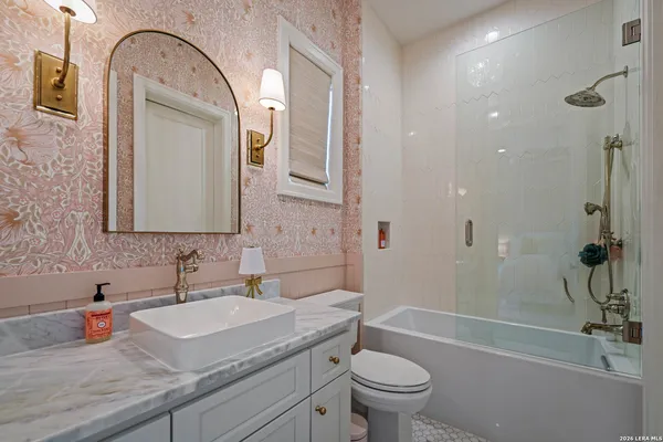 a bathroom with a granite countertop sink a toilet and shower