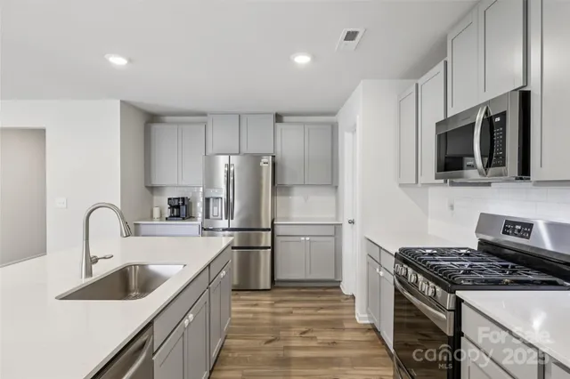 a kitchen with stainless steel appliances a sink stove and refrigerator