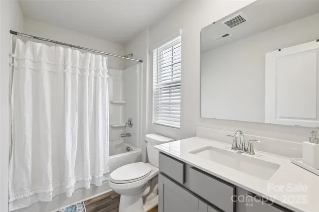 a bathroom with a granite countertop sink and a toilet