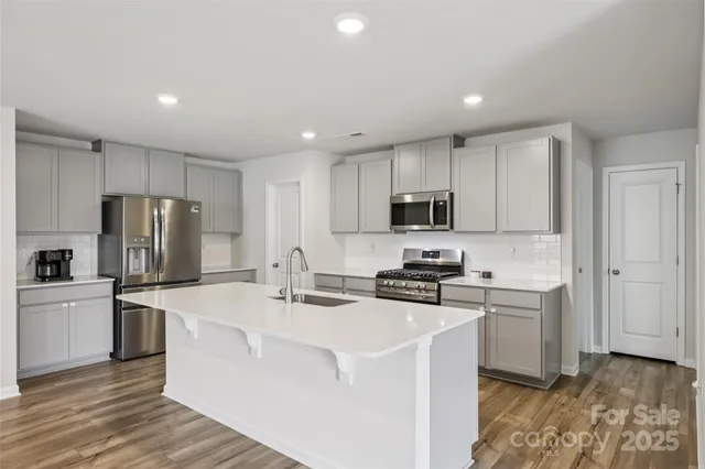 a kitchen with stainless steel appliances a sink a stove a refrigerator cabinets and a counter top space