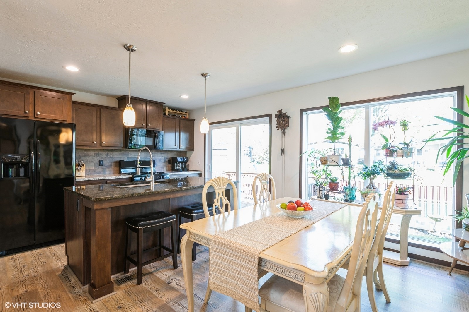 206 Big Peninsula Road Elgin, IL 60123 - Photo 5 of 23 a kitchen with stainless steel appliances kitchen island granite countertop a stove a refrigerator a sink a dining table and chairs with wooden floor