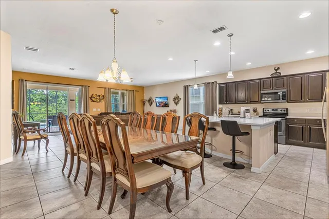 a open kitchen with stainless steel appliances granite countertop a stove a refrigerator a kitchen island a table and chairs