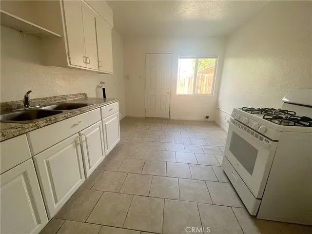 a kitchen with granite countertop white cabinets and white appliances