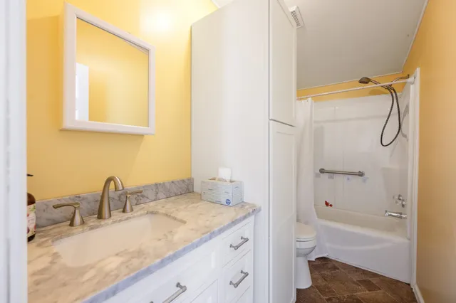a bathroom with a granite countertop sink toilet and shower